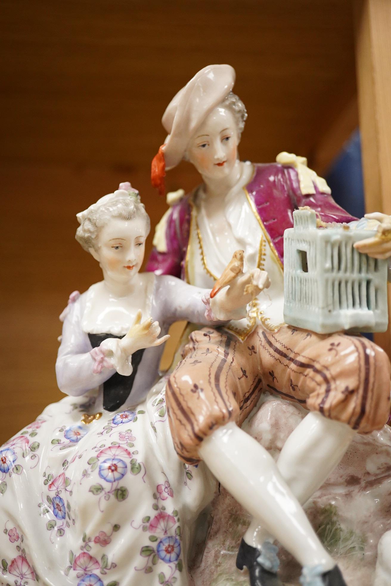 A German porcelain group of two figures with a bird cage and dog, 24cm high (Restored)